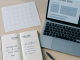 A candidate’s study desk with a notebook, generic exam timeline, laptop practice test, and