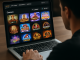 Over-the-shoulder view of a person browsing an organised casino games catalogue on a laptop.